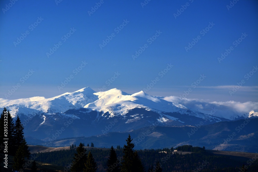 Spring landscape with mountain tops covered with snow