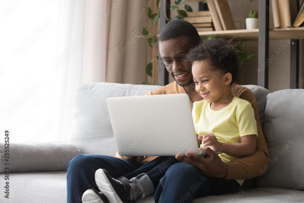 Naklejka premium African American father teaching toddler son to use laptop