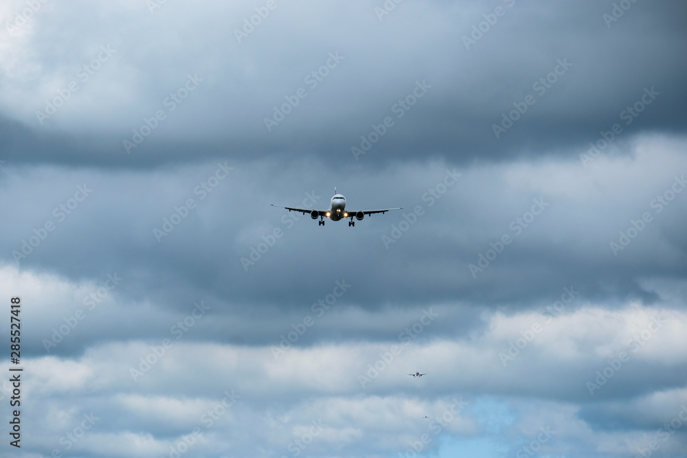 Airplane in landing approach with dark cloudscape