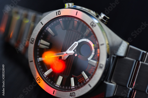 Luxury watch under colored light, close-up, black background