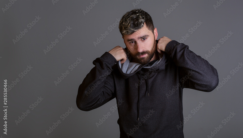 Stylish man on a gray background. Model tests of a man in a tracksuit. Men's hairstyle