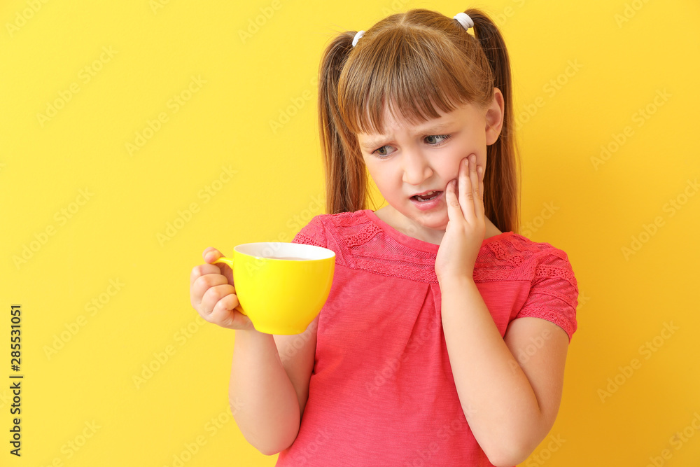 Little girl with sensitive teeth and cup of tea on color background Little girl with sensitive teeth and cup of tea on color background