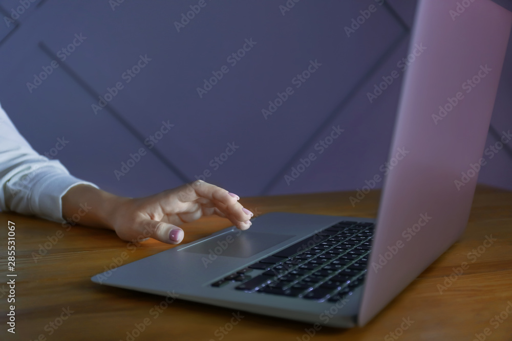Woman working on laptop at table in evening Woman working on laptop at table in evening