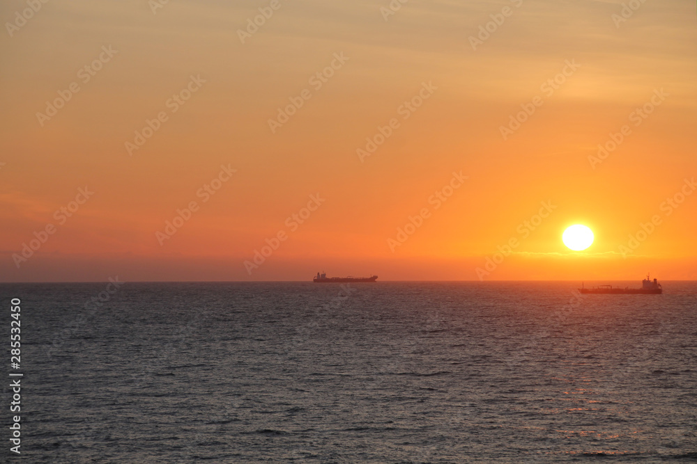 Seat at sunset with ships at the horizon 