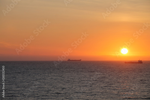 Seat at sunset with ships at the horizon 