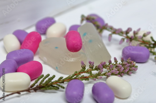 Dragee for refreshment of breath. Different color. Also peppermint candies. Lying on a white surface. Nearby are sprigs of heather.