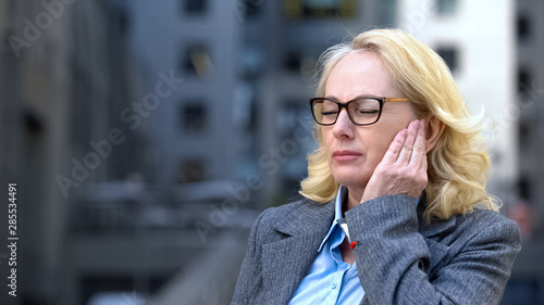 Fotografie Senior lady formal suit feeling jaw pain, lymph nodes inflammation, health care