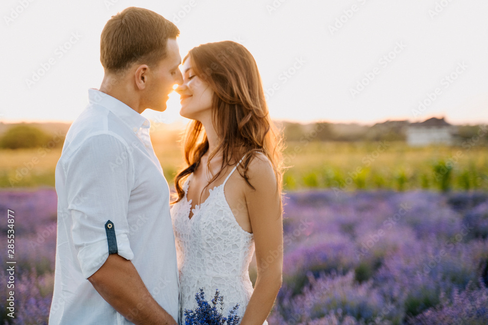 Sensual Couple in Lavender Field Romantic Time. Beautiful Young People Hug, Kiss Outdoor Medium Shot. Attractive Woman Hold Bouquet. Caucasian Man and Girl Embrace on Purple Flower Meadow Sensual Couple in Lavender Field Romantic Time. Beautiful Young People Hug, Kiss Outdoor Medium Shot. Attractive Woman Hold Bouquet. Caucasian Man and Girl Embrace on Purple Flower Meadow