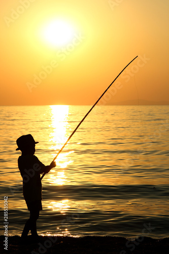 Silhouette of a boy with a fishing rod