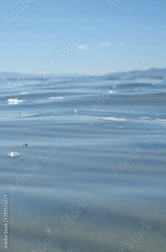 The wavy salt lake water and bubbles in the summer sunlight. 