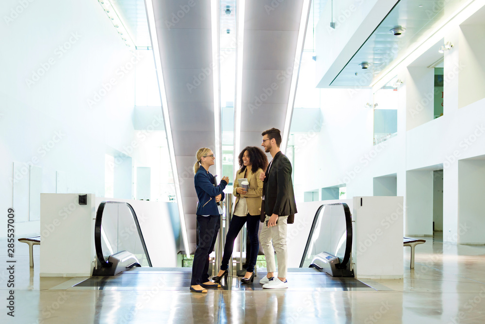 Young business people talking at an escalator Young business people talking at an escalator