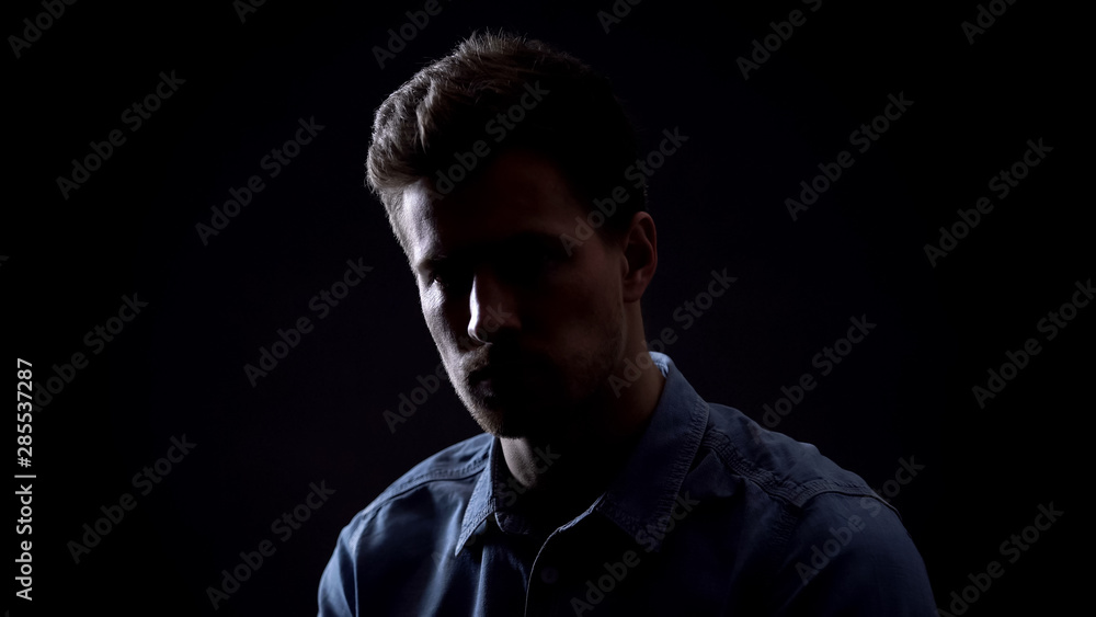 Young man looking at camera isolated on black background, personality dark side