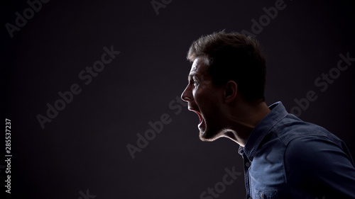 Frustrated man emotionally screaming isolated on black background, life problems