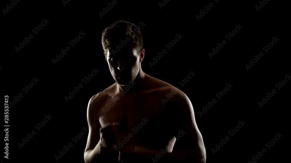 Topless free fighter preparing for sparing, dark background, shadow fight