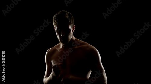 Topless free fighter preparing for sparing, dark background, shadow fight