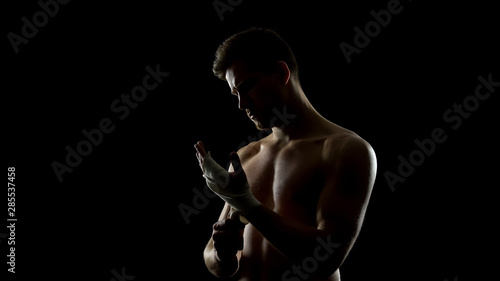 Male boxer using hand wraps, protecting wrists from injuries before punching