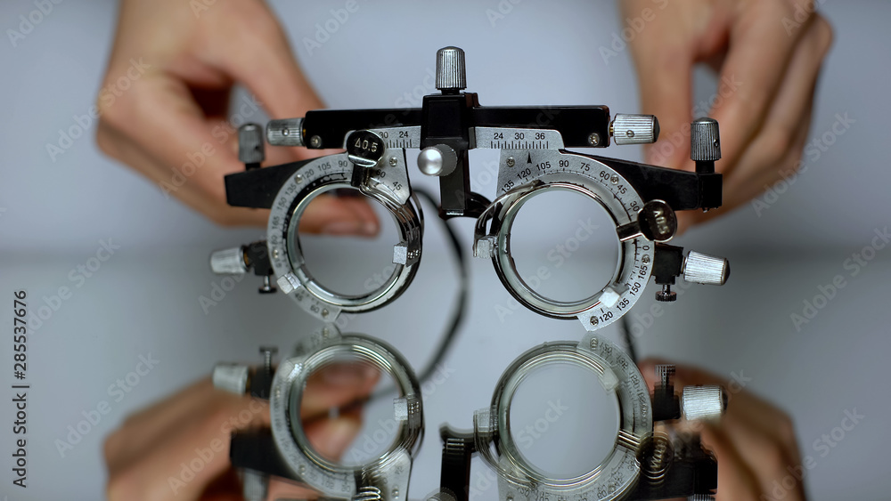 Hands putting special glasses for vision check, diagnosis of eye diseases Hands putting special glasses for vision check, diagnosis of eye diseases