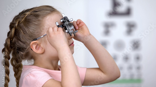 Εκτύπωση καμβά Optometrist putting phoropter on little girl, child complaining to see nothing