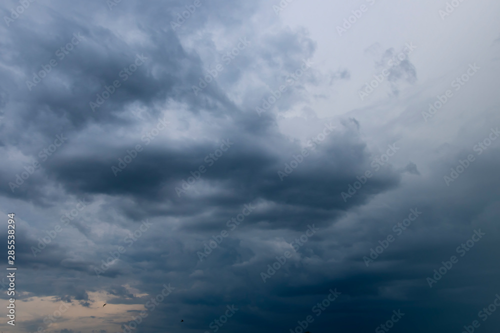 Dark thunder clouds on the blue sky. Abstract background with clouds on blue sky. Dark thunder clouds on the blue sky. Abstract background with clouds on blue sky.