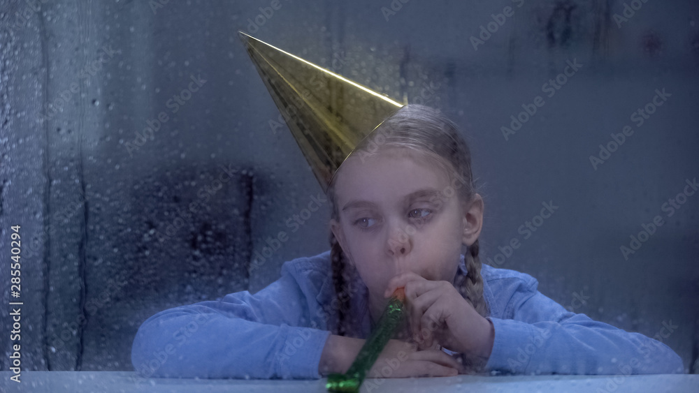Αυτοκόλλητο Upset girl in birthday hat blowing party horn on rainy day, celebrating alone