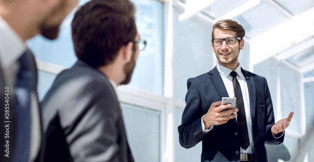 businessman with a smartphone standing in his ofiice businessman with a smartphone standing in his ofiice
