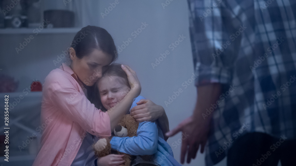 Fototapeta premium Mother hugging daughter, protecting from angry father, harassment in family
