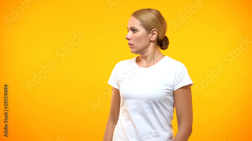 Fotografie Scared young lady looking left on bright background, frightened person, phobia