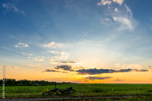 Bicycle lies on the ground, beautiful bright sunset