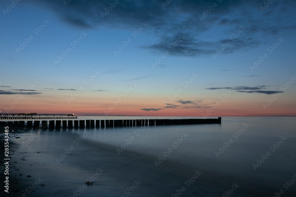 scenic seaside view with wooden stages and seabridge at the blue hour