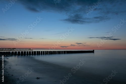 scenic seaside view with wooden stages and seabridge at the blue hour