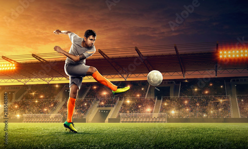 Professional soccer player in action with a ball on a soccer field. Dramatic night sky