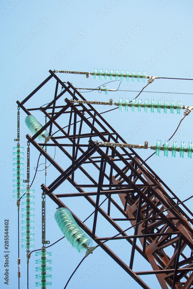 Bottom view on high voltage power lines against the blue cloudless sky