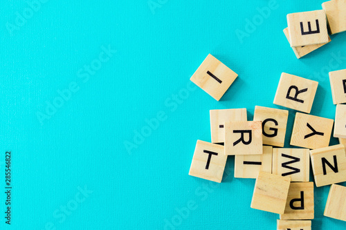 Billede på lærred Pile of wooden letters on the surface of a blue background, selective focus