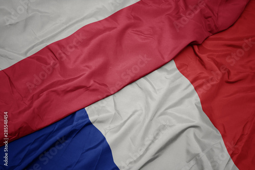waving colorful flag of france and national flag of poland.