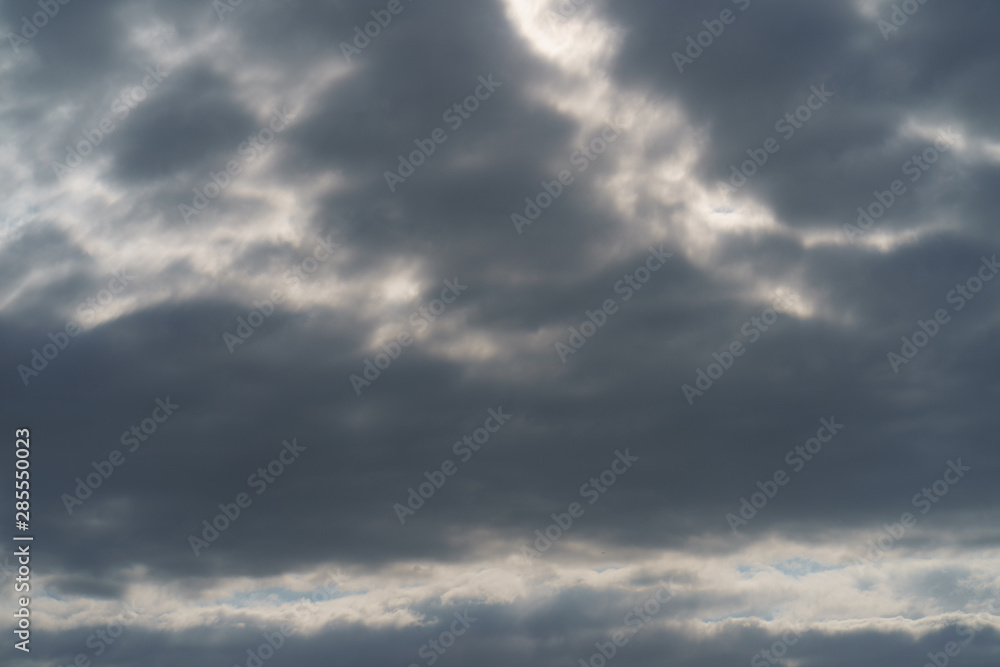 Textured, bright gray and white cumulus clouds in sky over the Atlantic ocean. Sunny summer day. Natural lights background. High resolution image. 
