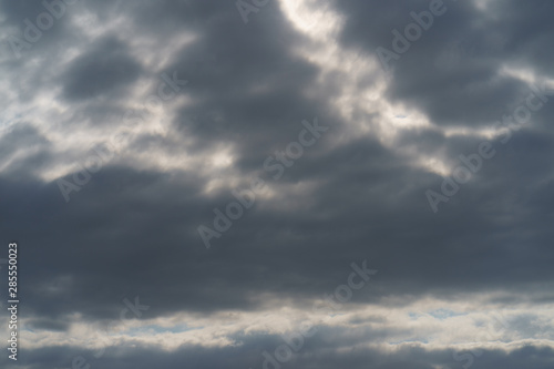 Textured, bright gray and white cumulus clouds in sky over the Atlantic ocean. Sunny summer day. Natural lights background. High resolution image. 