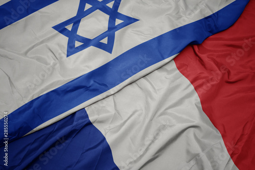 waving colorful flag of france and national flag of israel.