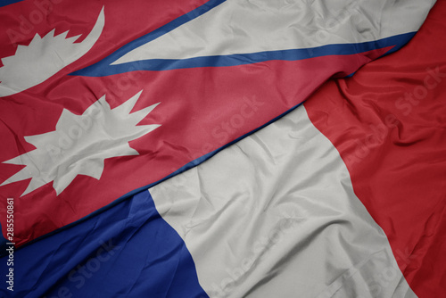 waving colorful flag of france and national flag of nepal.