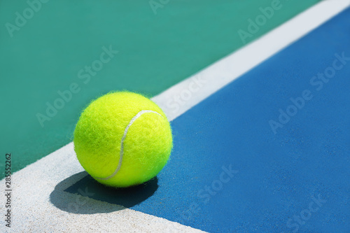 Sport concept with tennis ball on white line in the corner of hard tennis court. © IrynaV