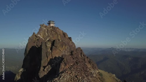 High angle scenic drone footage of a monastery or fire lookout on a craggy mountain top