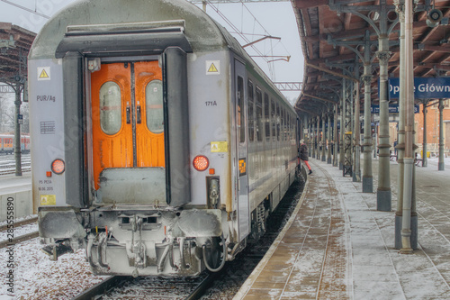 last car in the train on the platform, rail travel in winter, train punctuality and lateness, woman getting on the train, snow-covered railway carriage