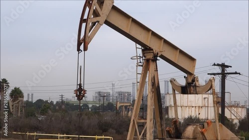 Industrial oil derrick pumping with palm trees in background