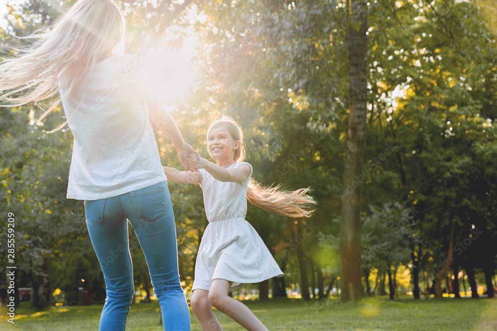 Naklejka premium Mother and little daughter dancing, having fun in a park