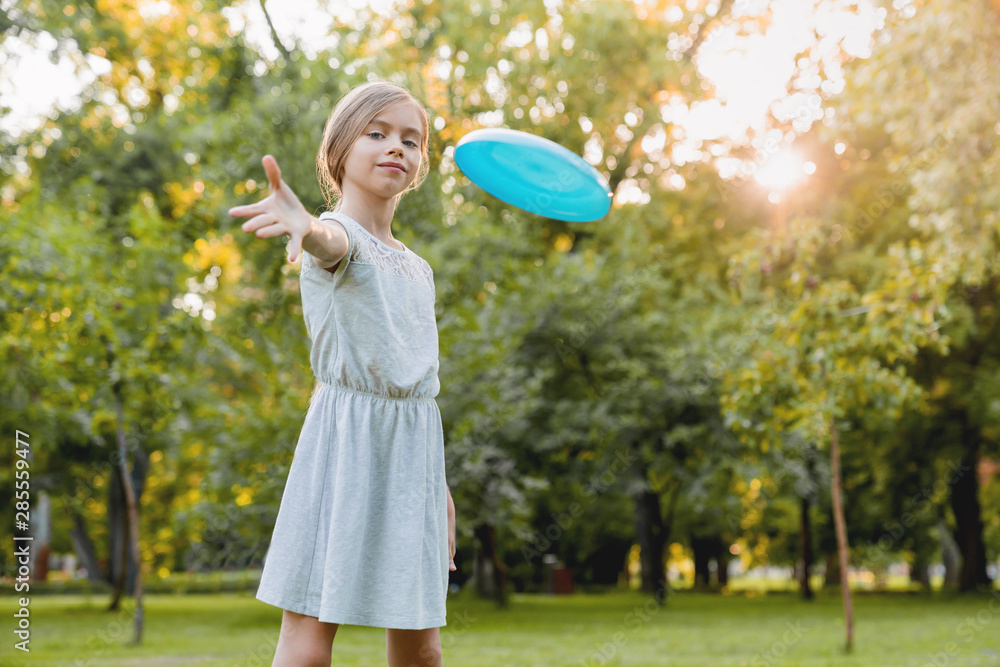 Cute smiling little girl playing frisby and having fun in city park Cute smiling little girl playing frisby and having fun in city park