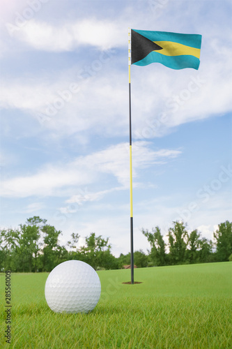 Bahamas flag on golf course putting green with a ball near the hole