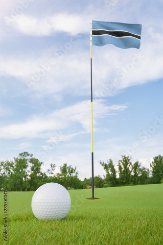Botswana flag on golf course putting green with a ball near the hole