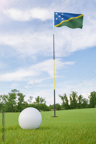 Solomon Islands flag on golf course putting green with a ball near the hole