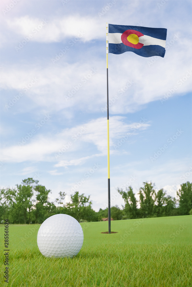 Obraz premium Colorado flag on golf course putting green with a ball near the hole
