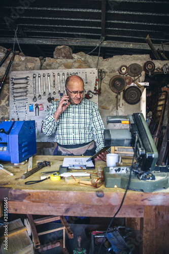 Senior carpenter talking on the phone in his workshop