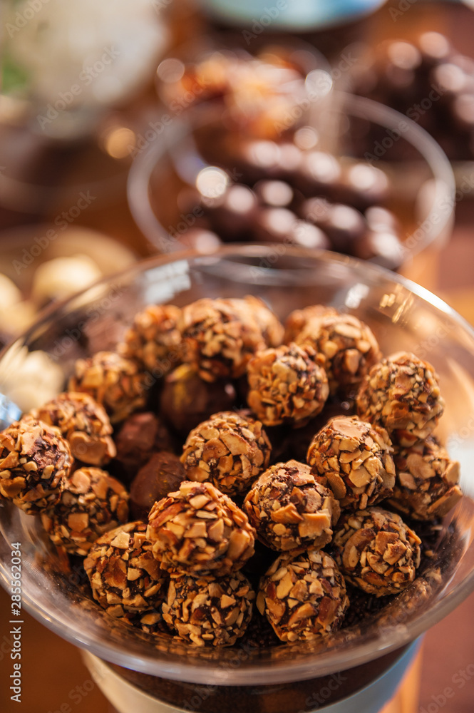 Nut and chocolate covered round candies in a glass bowl. Nut and chocolate covered round candies in a glass bowl.